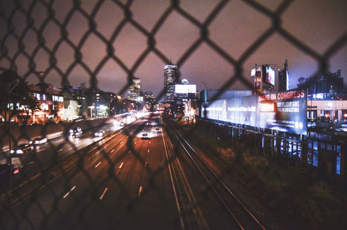 A city scape seen through a chain link fence